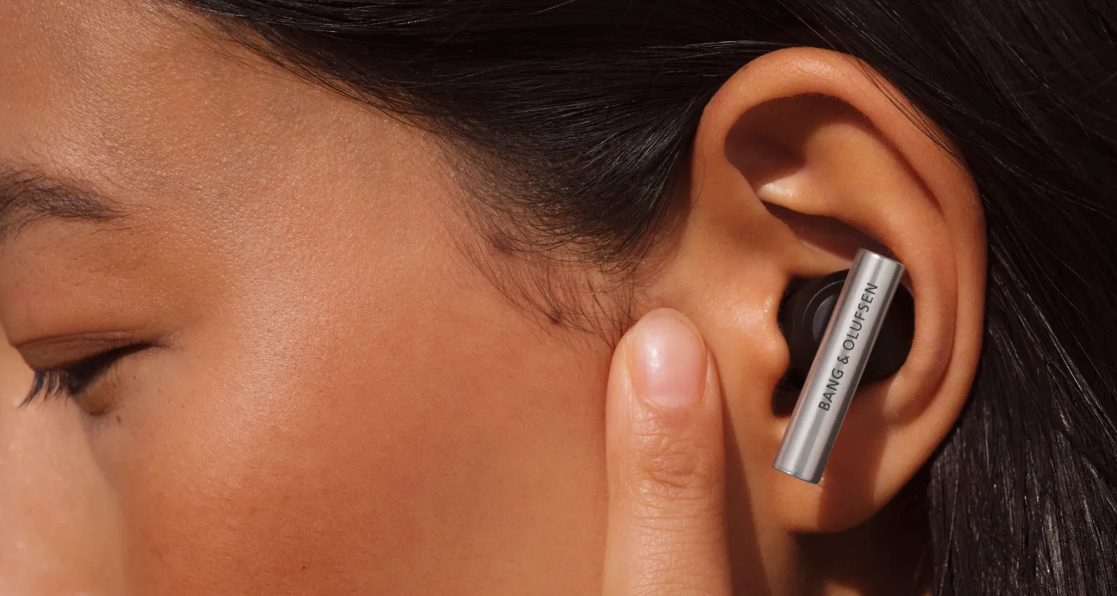 Beo Grace plugged in an ear and a woman touching the skin in front of her ear