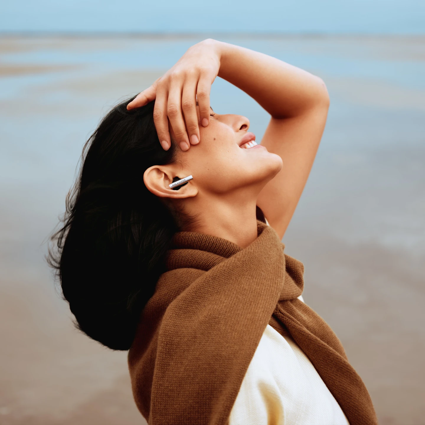 Side face of a woman smiling who's wearing Beo Grace and feeling the music