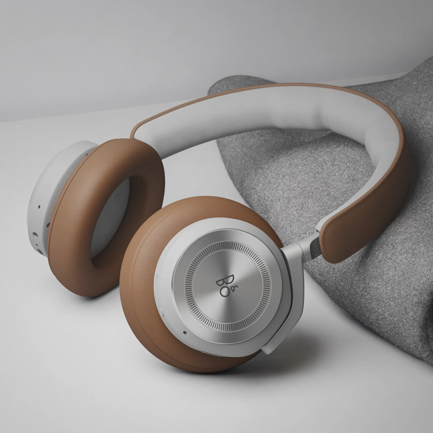 Beoplay HX in the color variant Timber, laying on a grey blanket