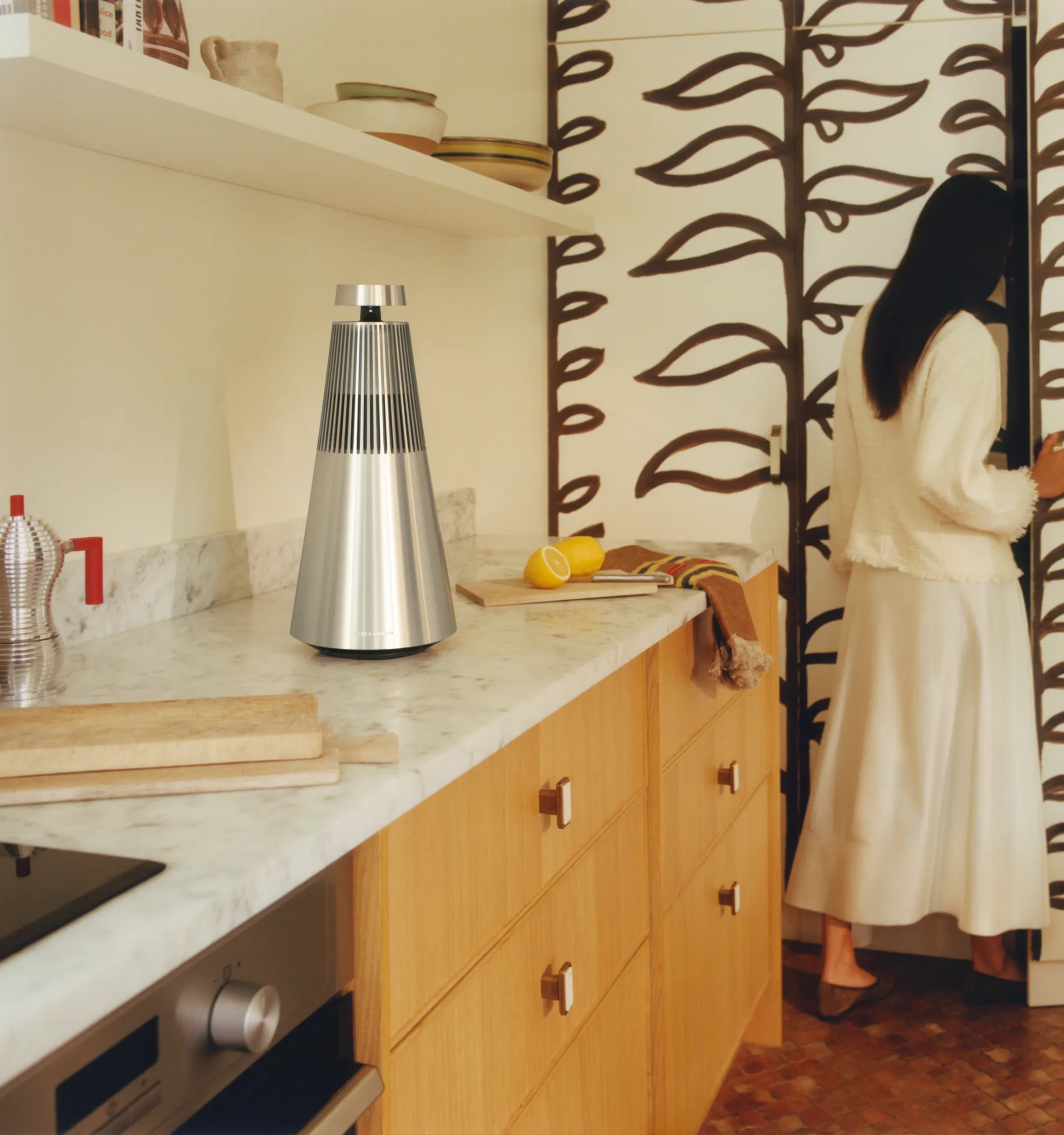 Beosound 2 standing on a counter in a modern kitchen with woman standing on the side.