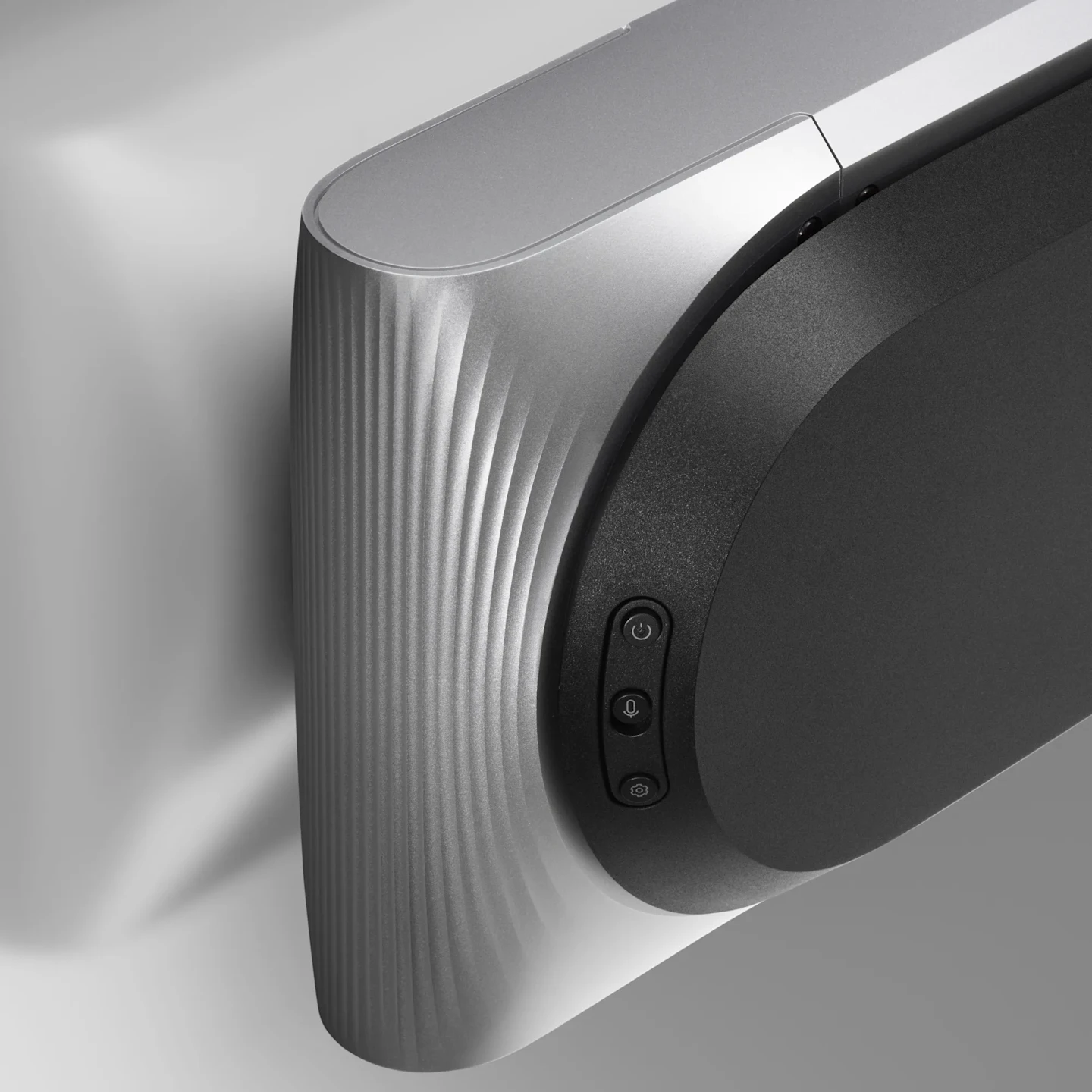 Close-up of a sleek silver and black Beosound Premiere Haute soundbar with ribbed texture and control buttons mounted on a wall.