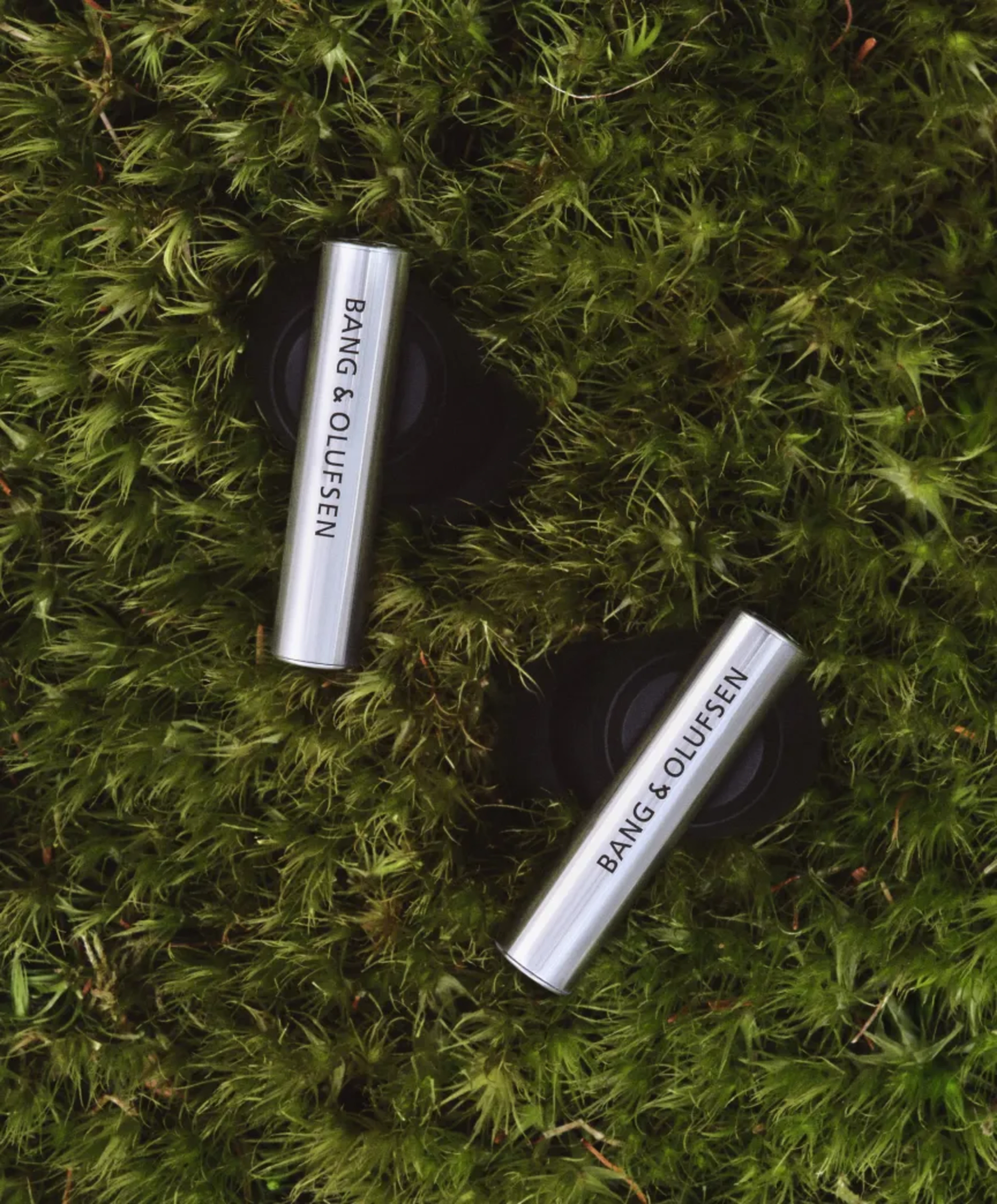 Pair of Beo Grace on the grass showing the aluminium bar of the earphones