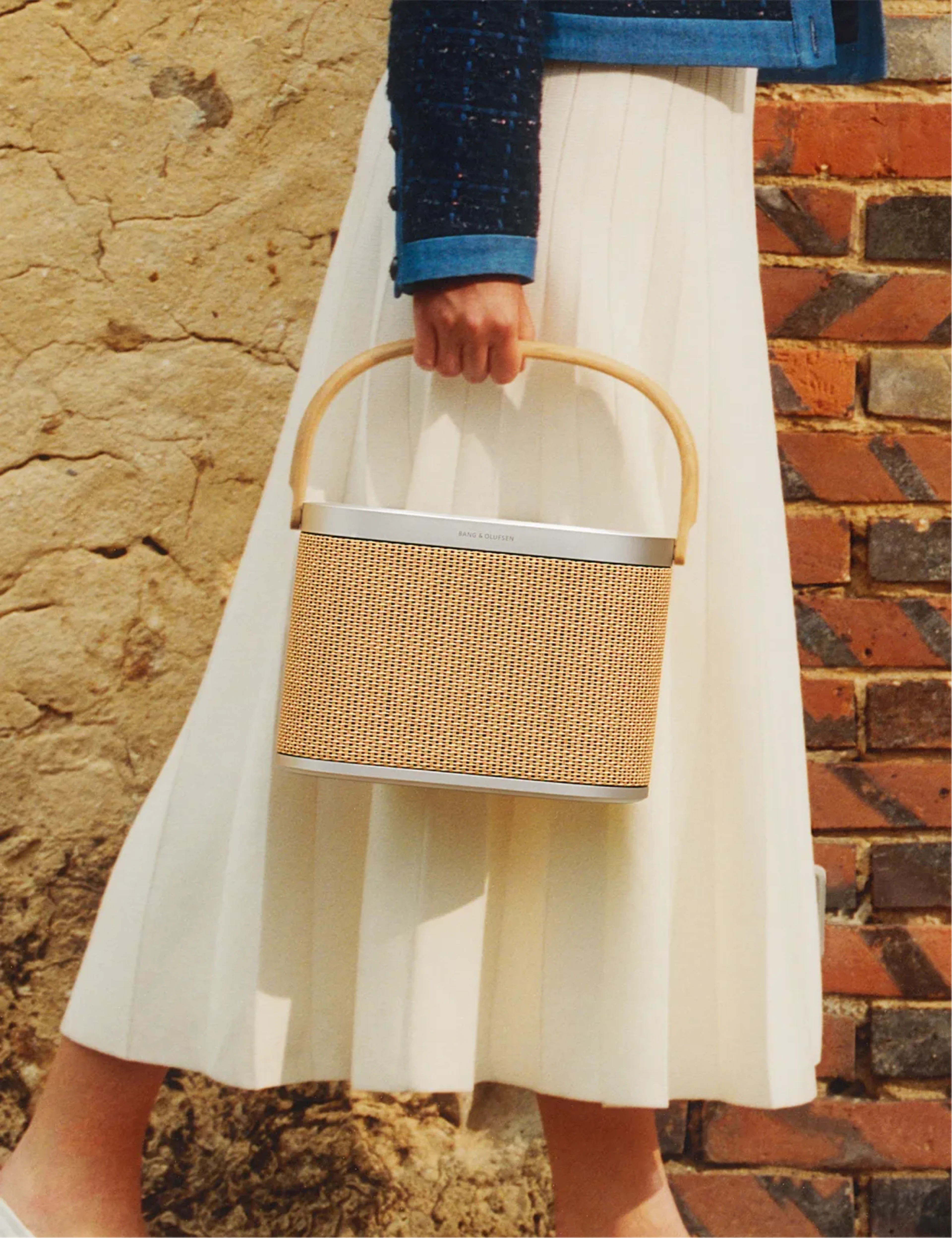 A woman wearing a skirt carries Beosound A5 in her hand